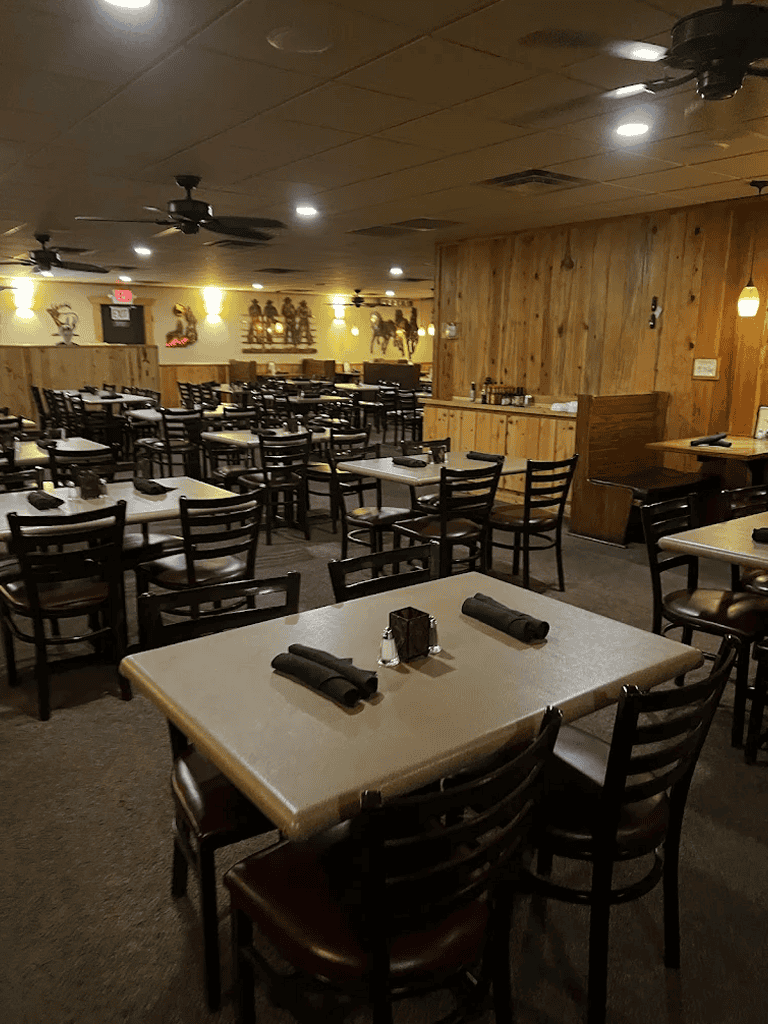 Spacious restaurant interior with wooden accents, black chairs, and ambient lighting, perfect for dining and gatherings.