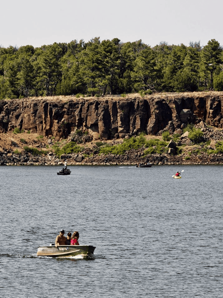 1. Boats on a river with rocky cliffs and green trees in the background.