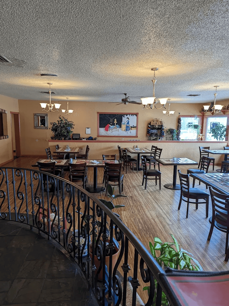 Cozy restaurant interior with wooden floors, chandeliers, and potted plants, perfect for dining in a welcoming atmosphere.