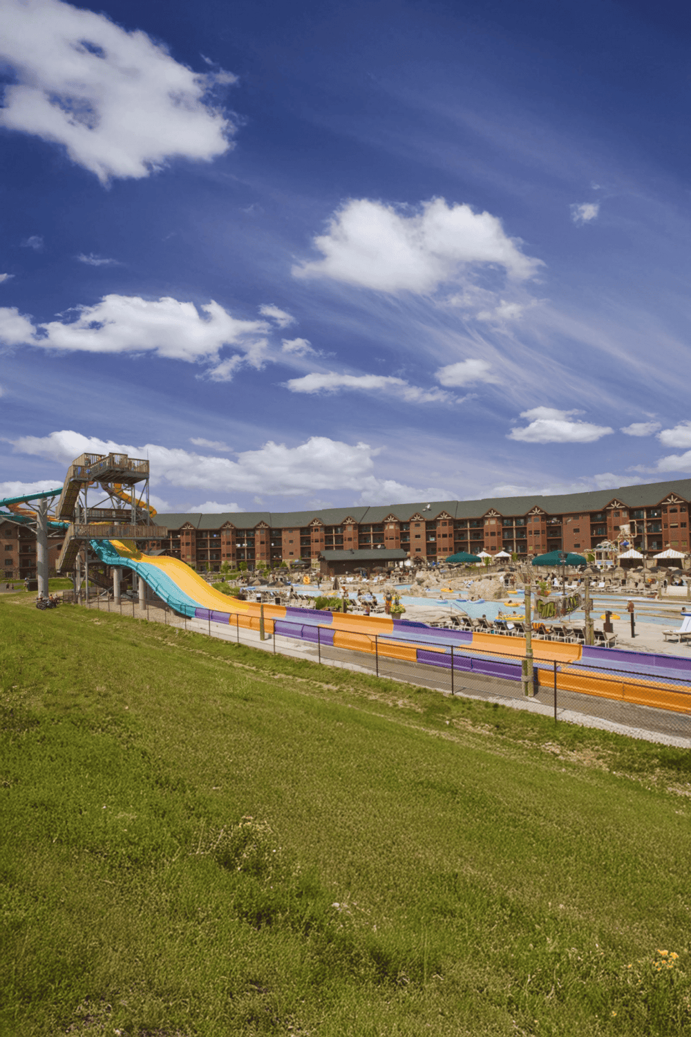 Water park with colorful slides and resort buildings under a bright blue sky.