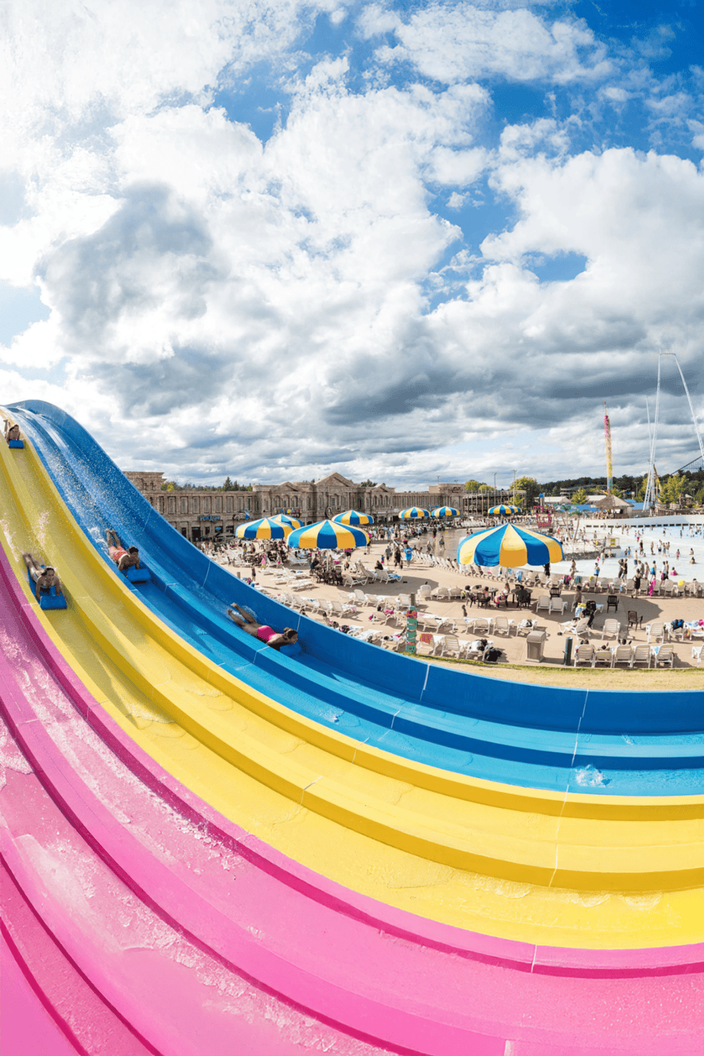 Colorful water slides at a large outdoor water park, families enjoying sunny day, blue skies, and water attractions.