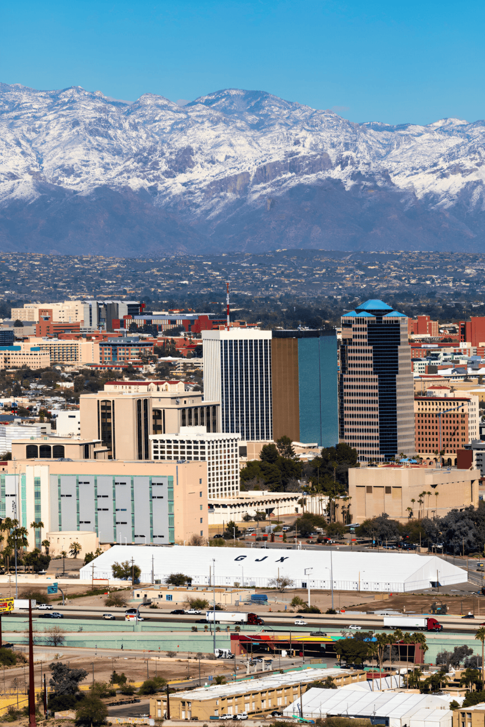 Mountain cityscape with skyscrapers and snow-capped mountains in the background.