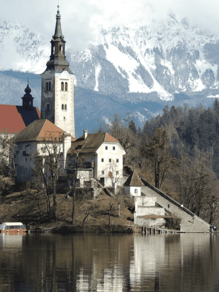 1. Charming European lakeside village with mountains backdrop, historic church, and scenic waterfront view.