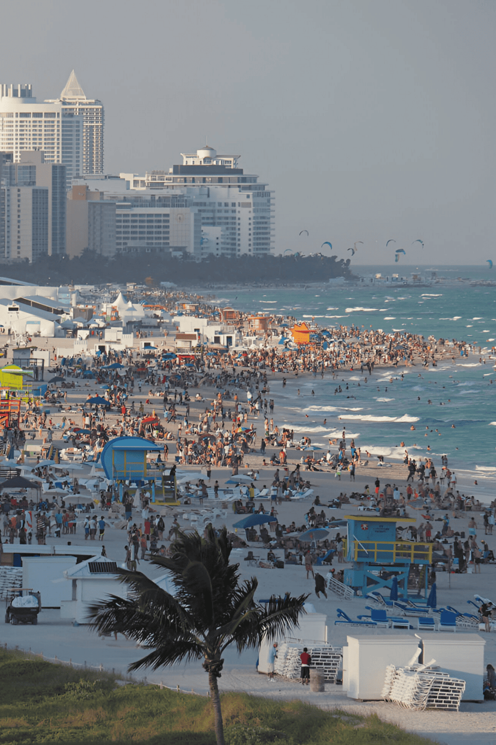 1. Sunset view of Miami beach with crowded shoreline and tall city buildings in the background.