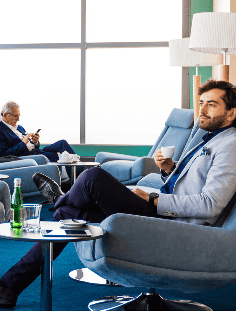 Business traveler relaxing in airport lounge, enjoying a coffee while waiting for departure.