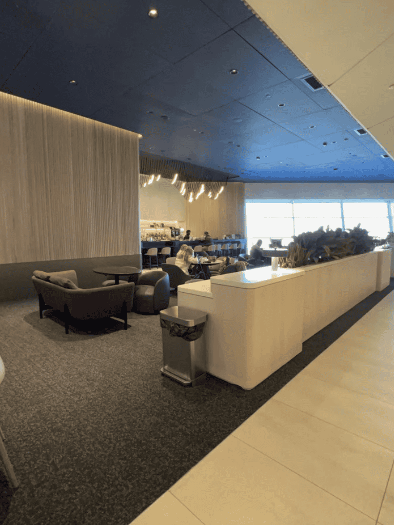 Modern airport lounge interior with seating and large windows for travelers.