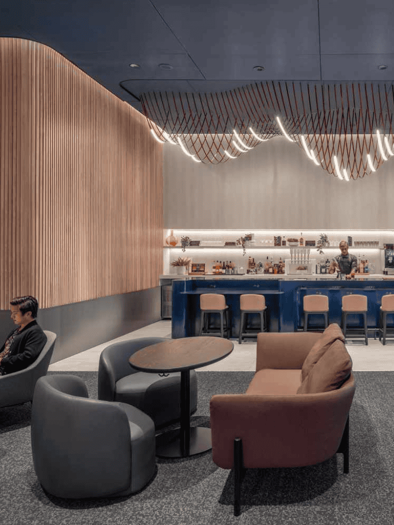 Modern airport lounge with comfortable seating and bar area for travelers.