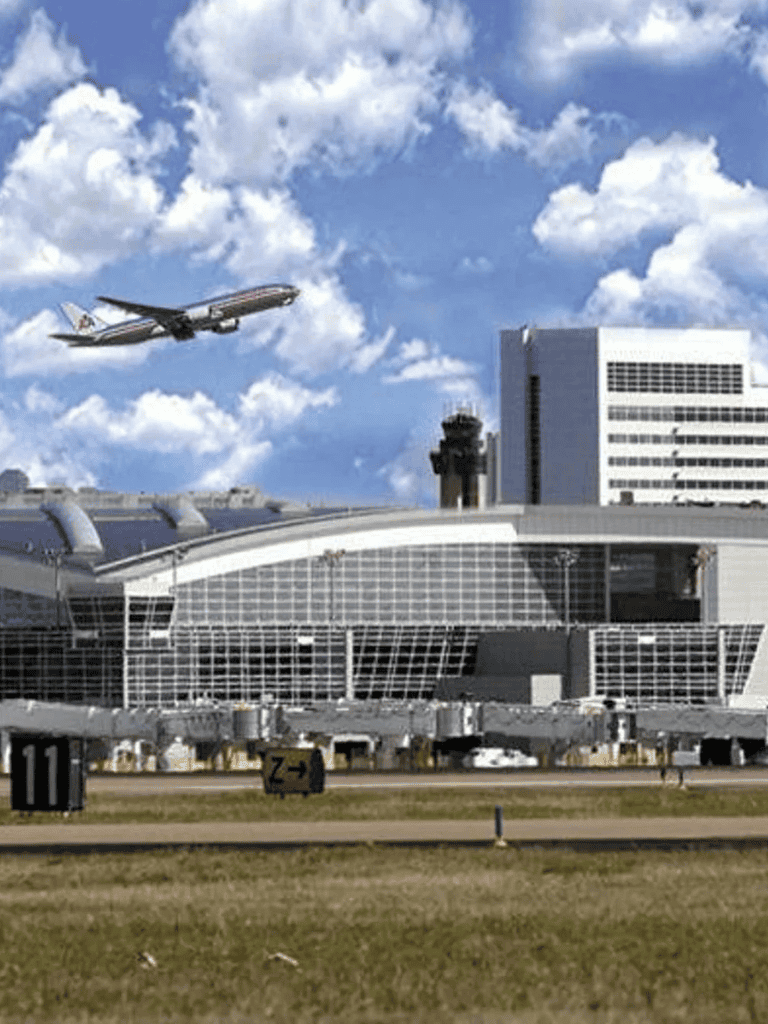 Airplane taking off from modern airport terminal with blue sky in background.