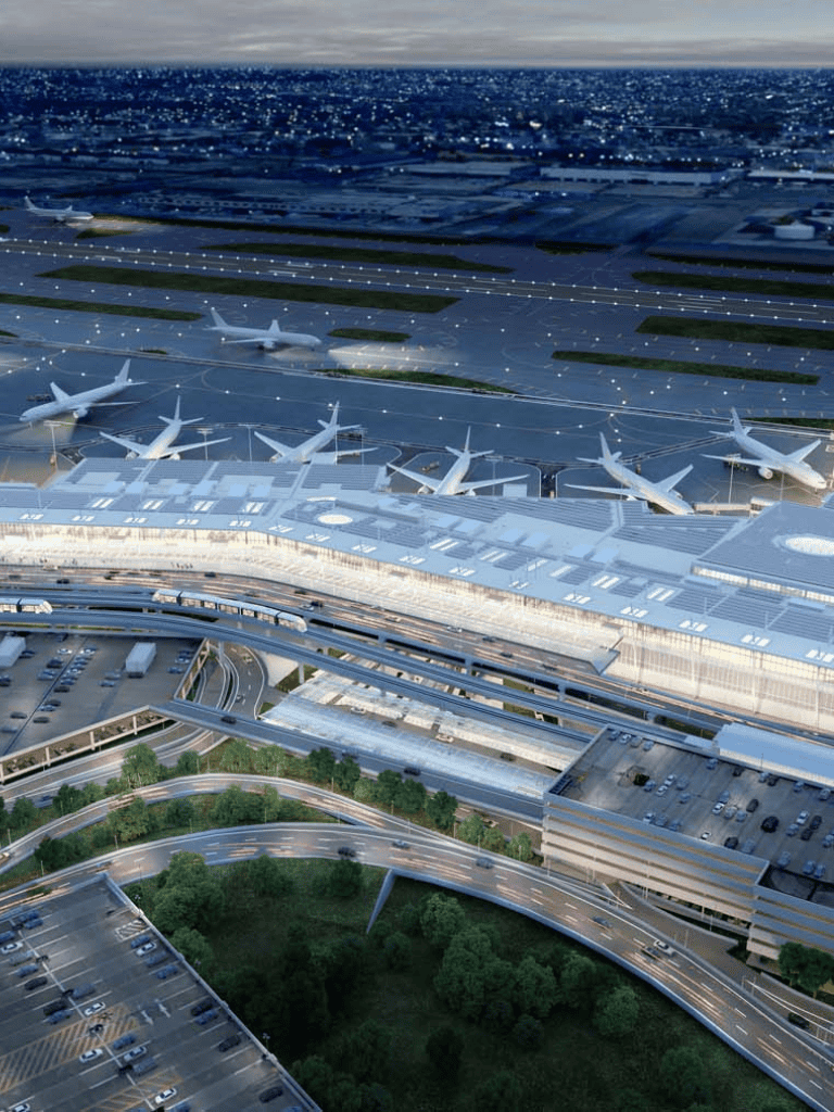 Modern airport terminal with airplanes, runways, and vehicular infrastructure under a cloudy sky.