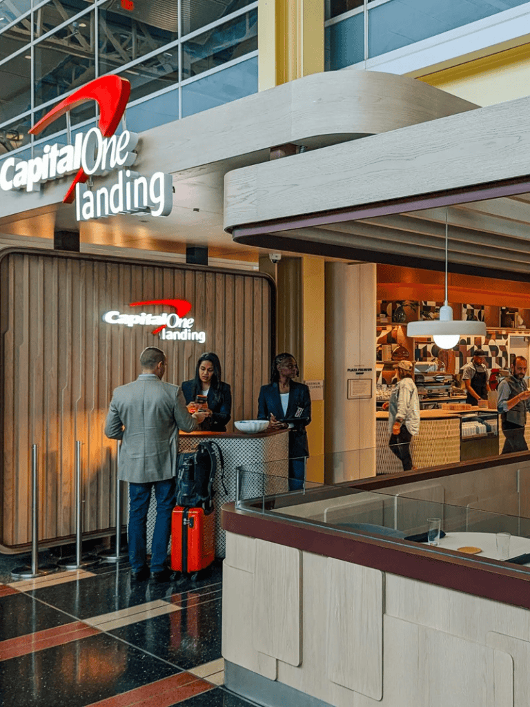 Flight check-in counter at Capital One Landing in an airport, travelers with luggage and staff assisting.