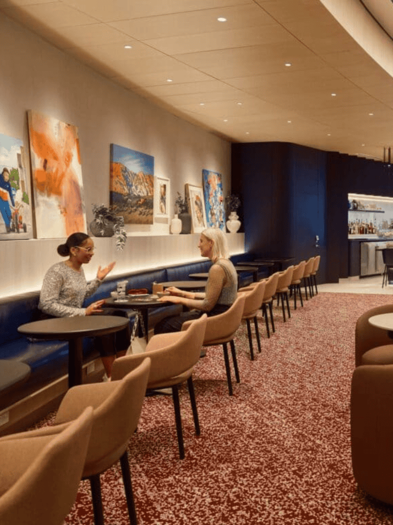 Cozy restaurant with modern decor, artwork, and two women enjoying a conversation at a table.