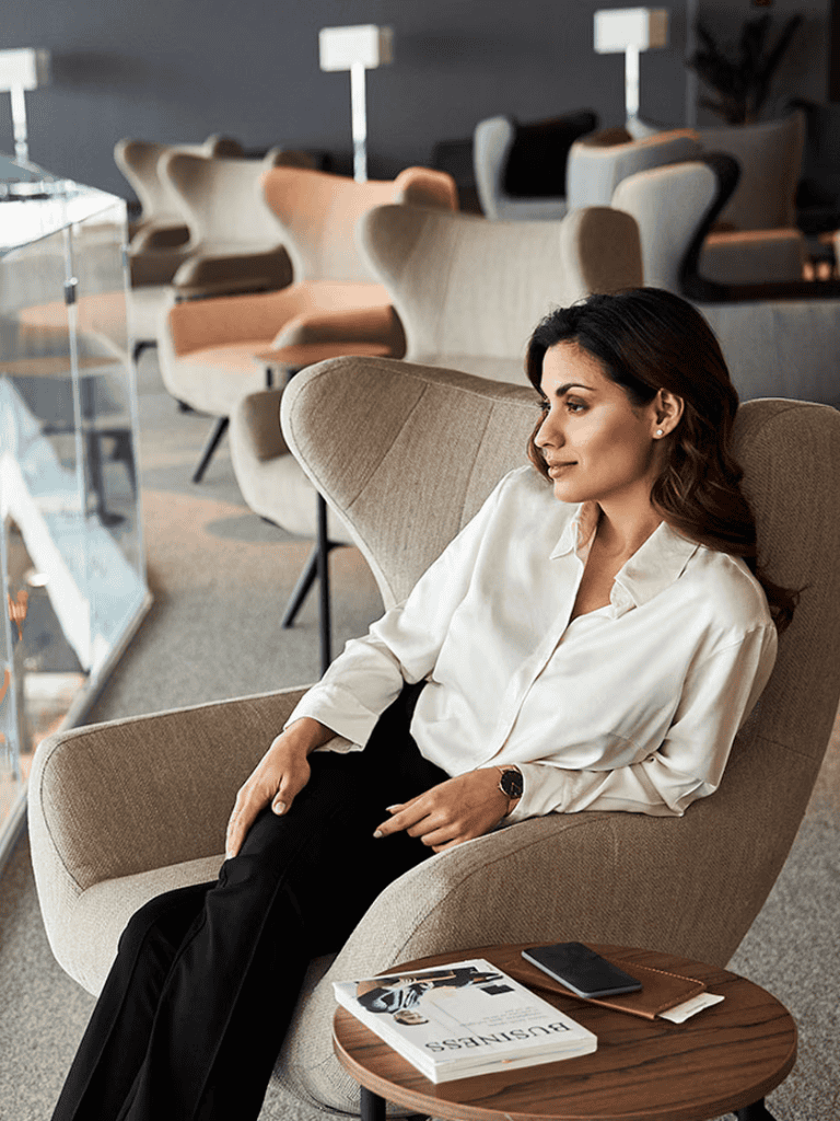 Relaxed woman sitting in a modern lounge area at QuestForDirections, seeking guidance and inspiration for travel plans.