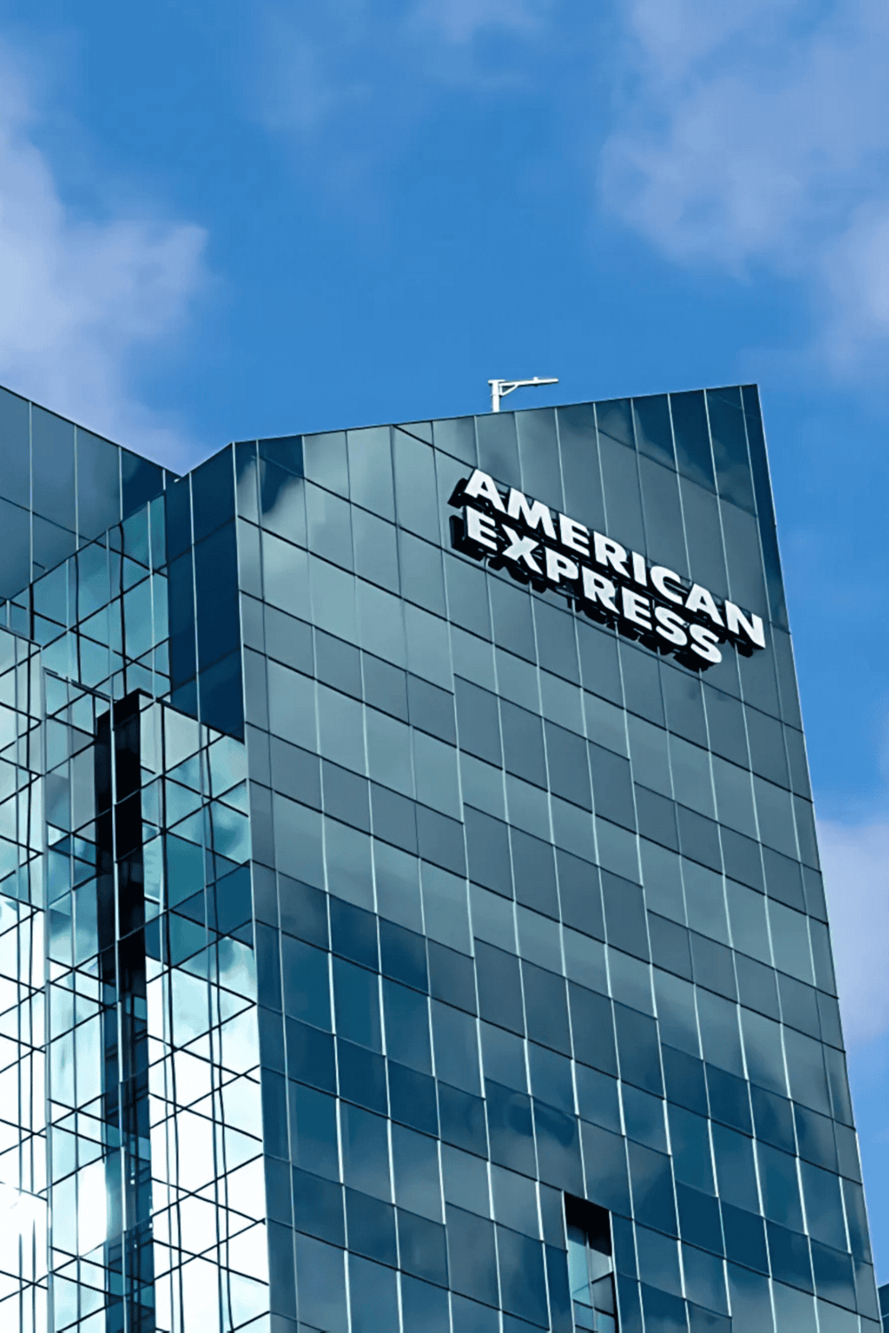 American Express corporate building with glass facade, modern architecture, and clear blue sky.