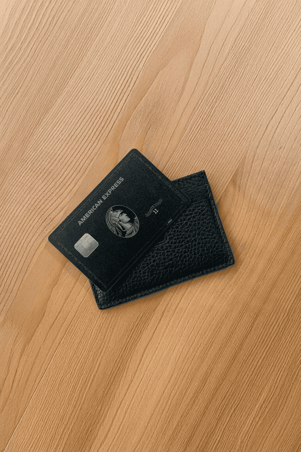 Credit card on black leather wallet on wooden surface.