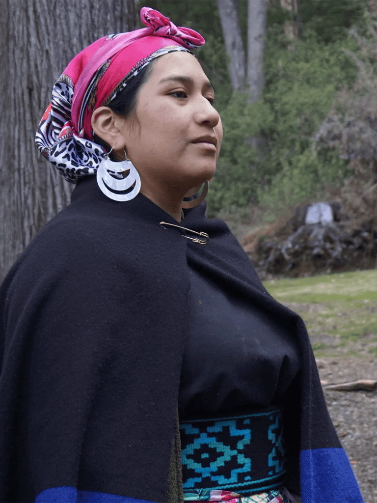 Colorful headscarf and traditional attire of Indigenous woman in natural outdoor setting for cultural exploration.