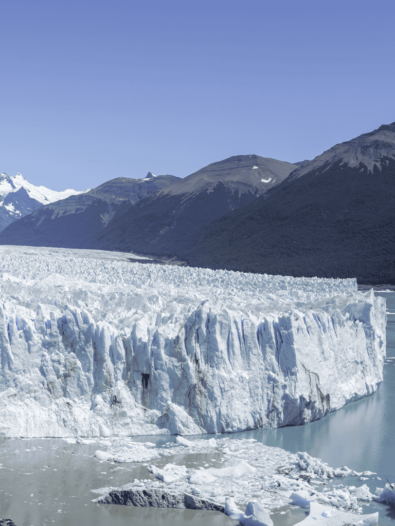 Majestic glacier in Alaska with snow-capped mountains in the background.