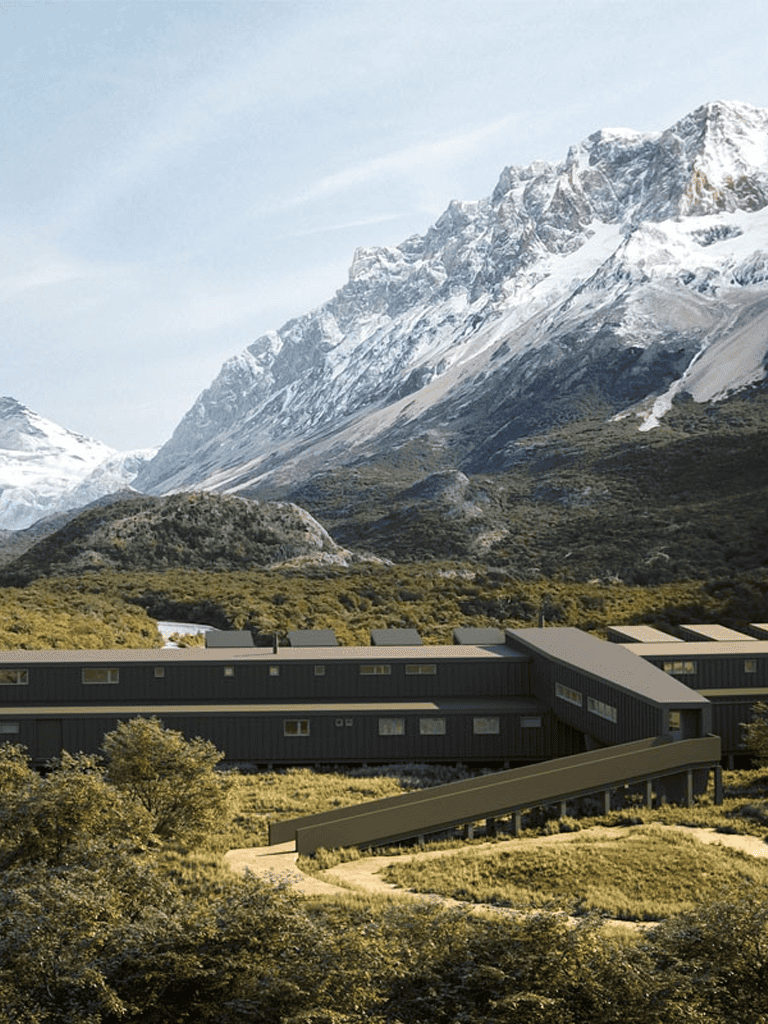 Snow-capped mountains with modern lodge in lush green valley, scenic travel destination.
