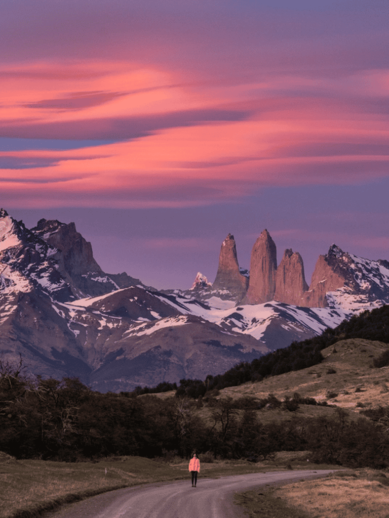 Vibrant sunset over Patagonian mountains in Chile, with a hiker on a scenic trail at dusk.