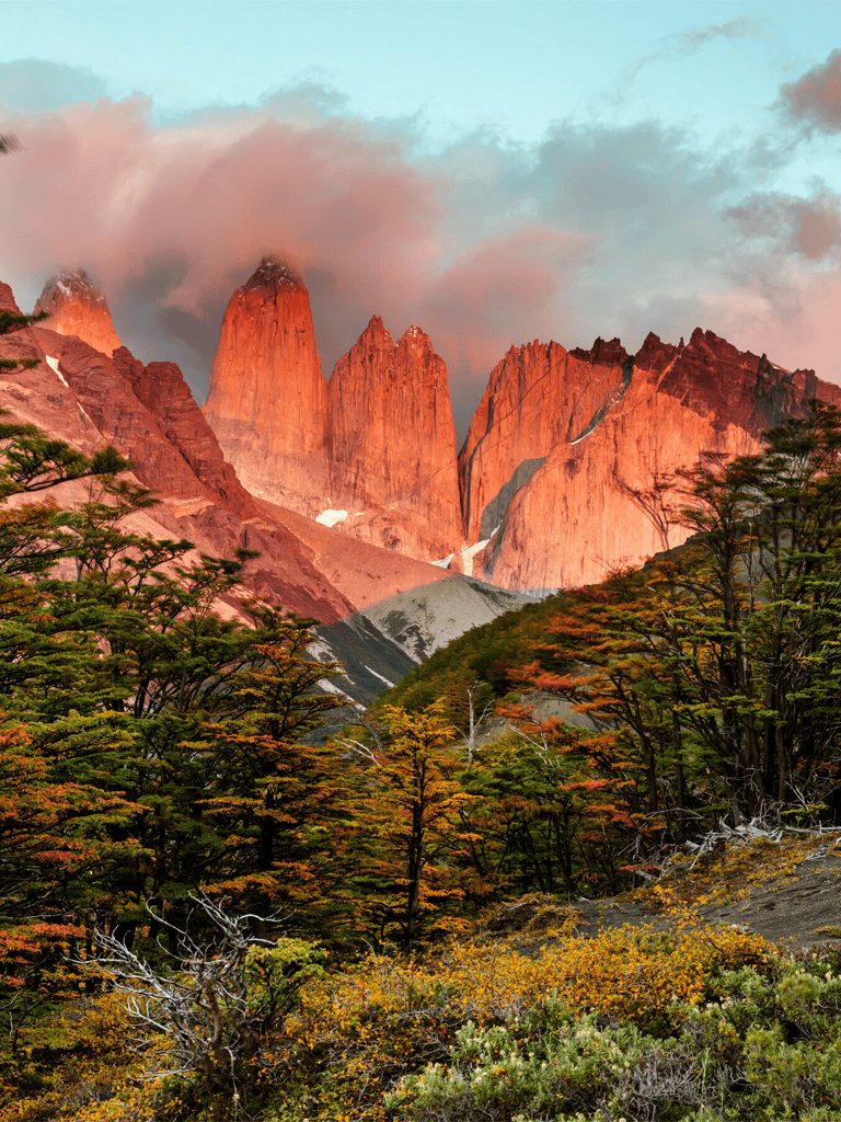 Majestic mountain landscape during sunset with vibrant fall foliage and dramatic clouds.
