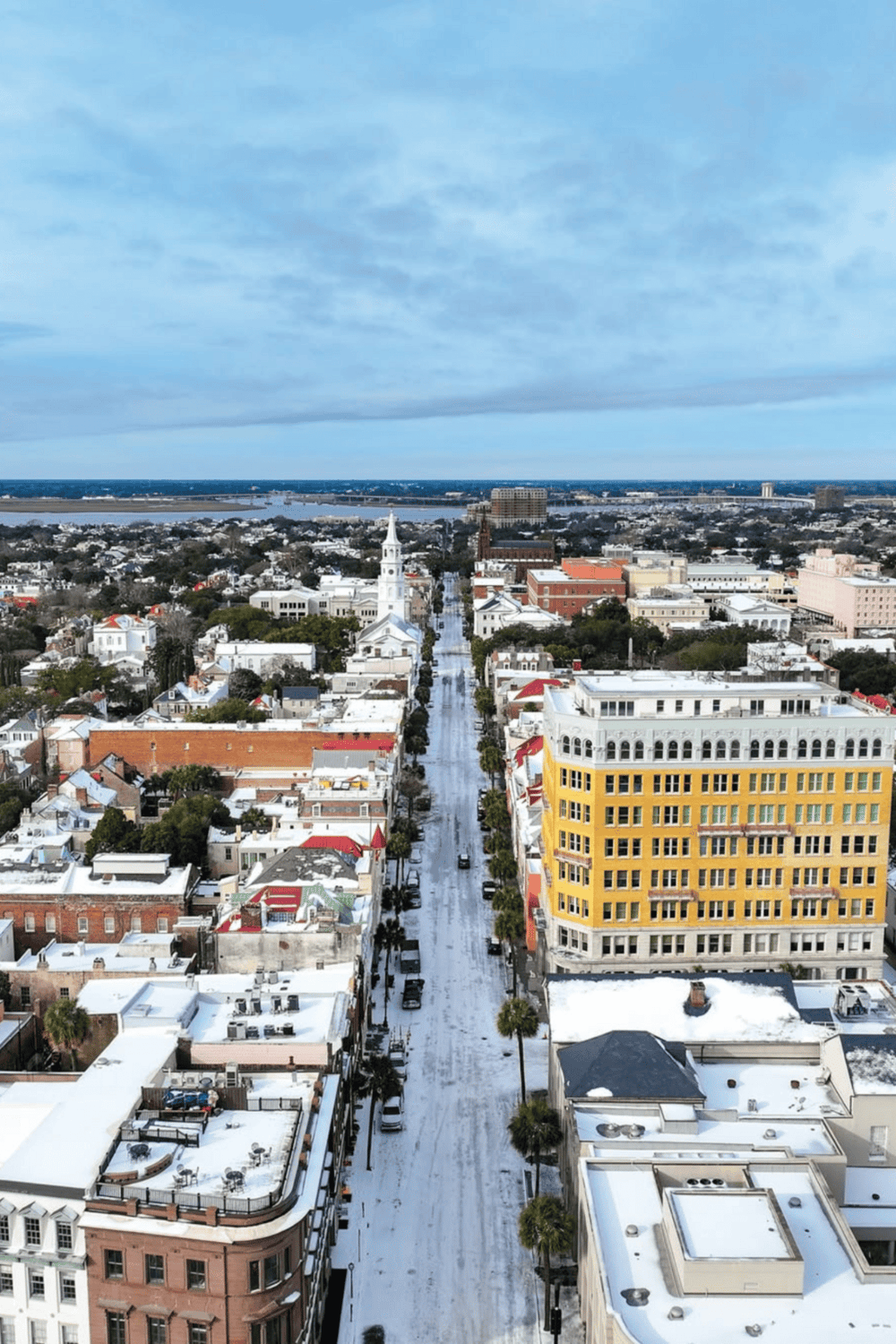 Snow-covered downtown street with historic buildings, clear skies, and water in the distance | QuestForDirections.