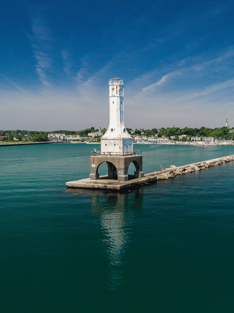 Lighthouse on pier in harbor with scenic waterfront view.