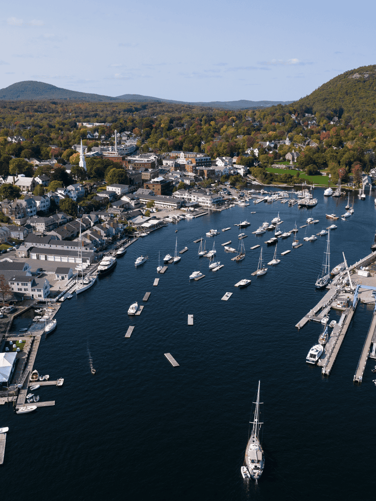 Picturesque harbor with sailboats and waterfront homes in a charming coastal town, perfect for maritime and travel enthusiasts.