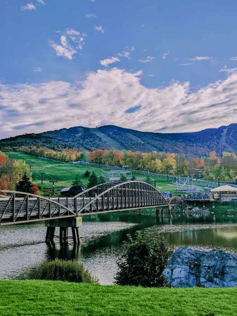 Lush landscape with mountain views, bridge over water, and vibrant fall foliage at QuestForDirections.