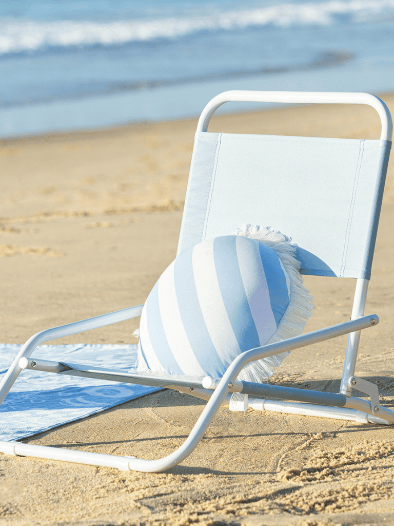 Relaxing beach chair with pillow on sandy shore, perfect for seaside vacation and relaxation.