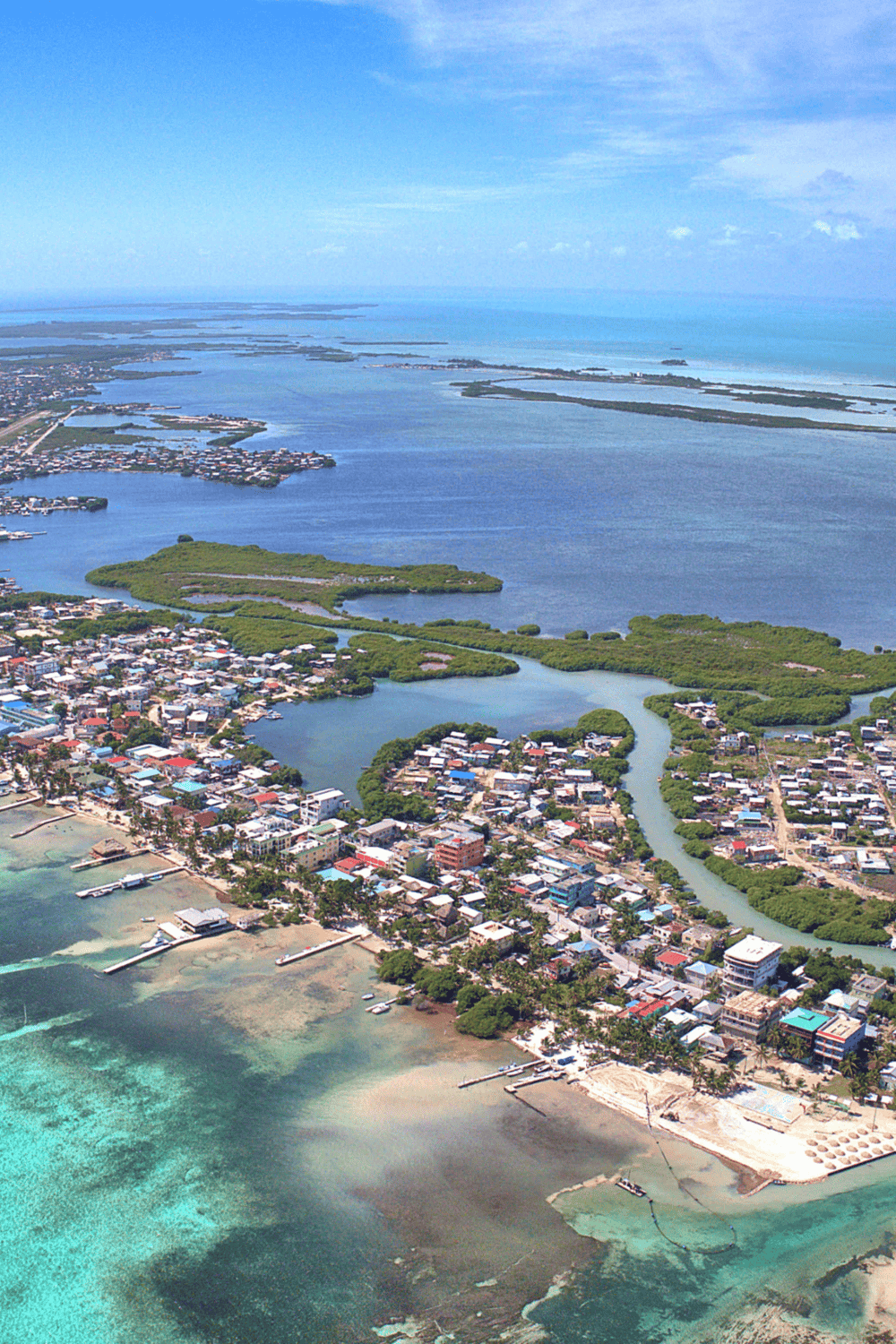 Aerial view of coastal town with waterways, boats, and lush green islands, showcasing scenic island travel and ocean navigation.