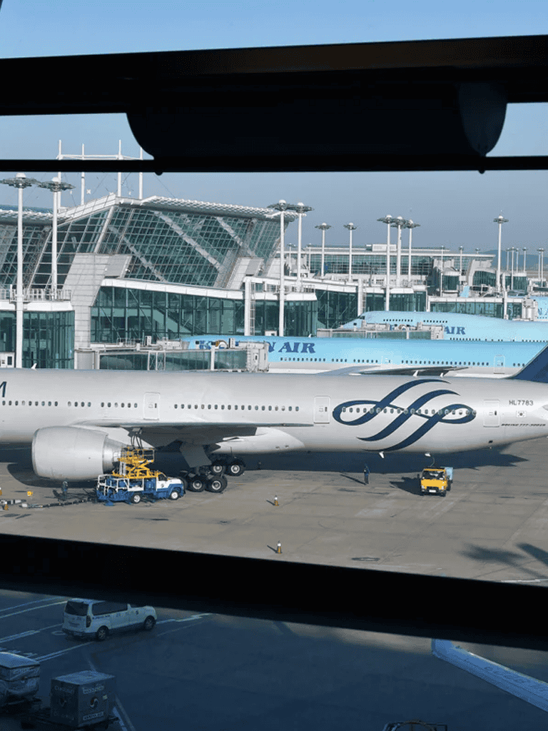 Airplane at an airport terminal with modern architecture and jet bridges, waiting for departure or arrival.
