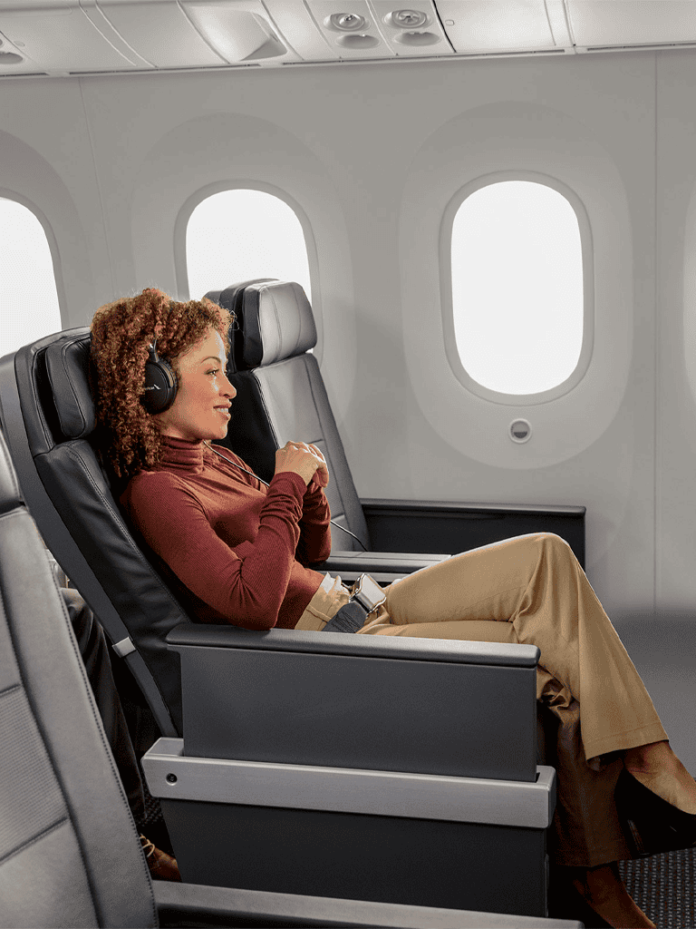 Relaxed woman enjoying in-flight entertainment on airplane seat during flight travel.
