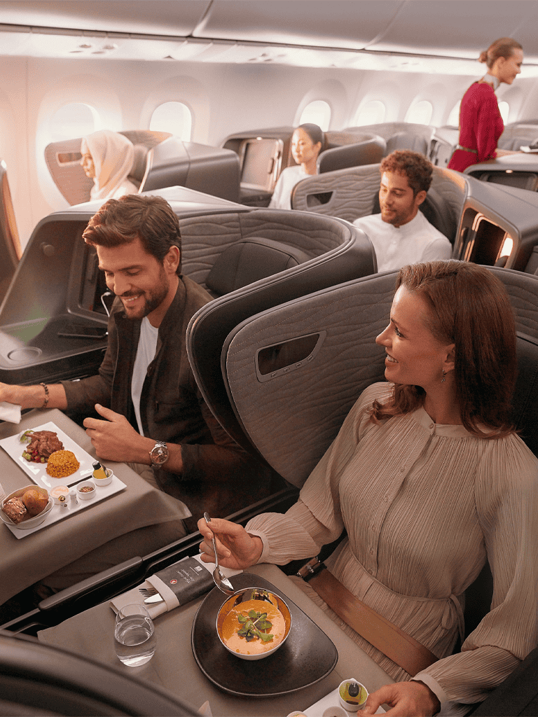 Elegant airline cabin with passengers enjoying gourmet meals and drinks, emphasizing premium inflight service and comfort.