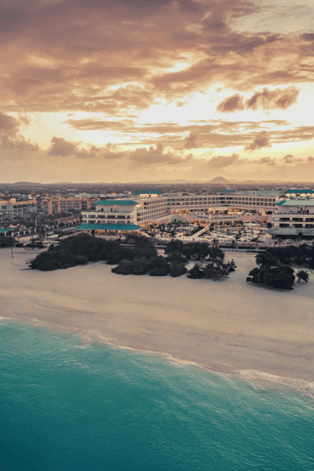 Luxury beachfront hotel with ocean views and scenic sunset in a tropical destination.