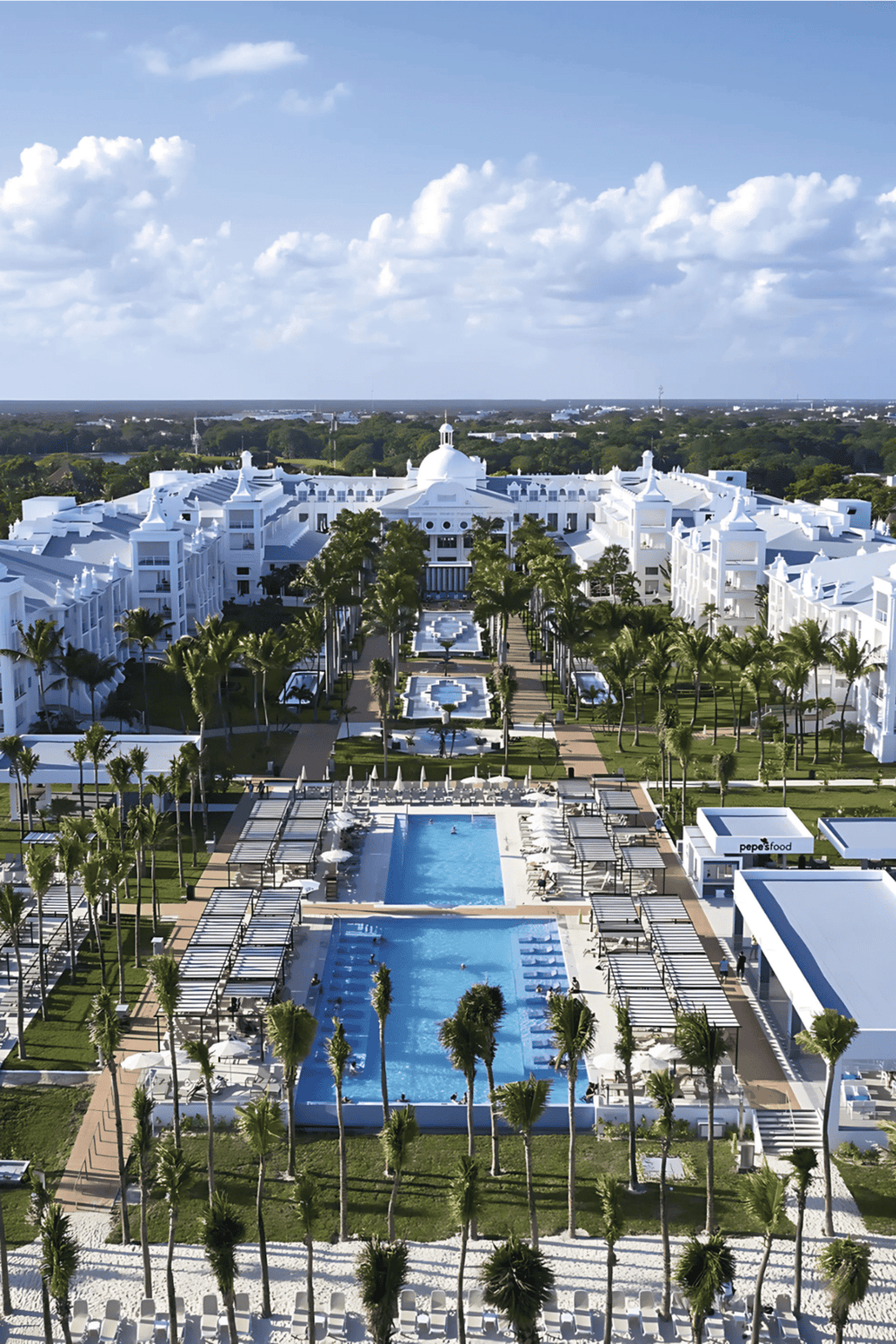 Luxury resort with pools, palm trees, and white architecture in a tropical setting.