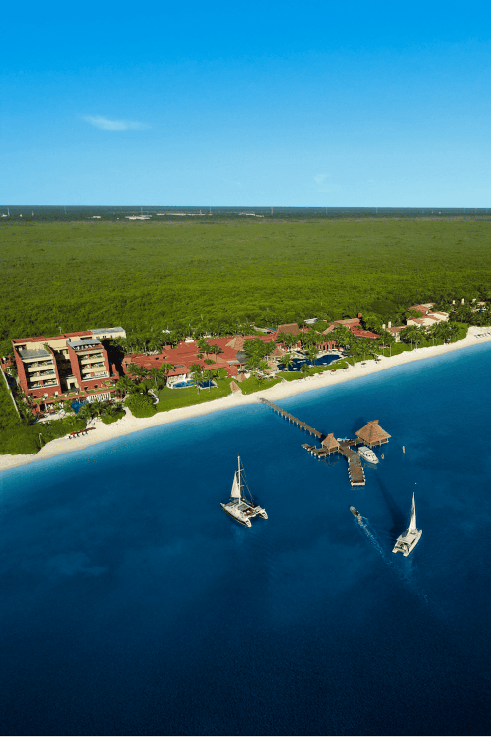 1. Aerial view of beachfront resort with boats docked and lush greenery in background.