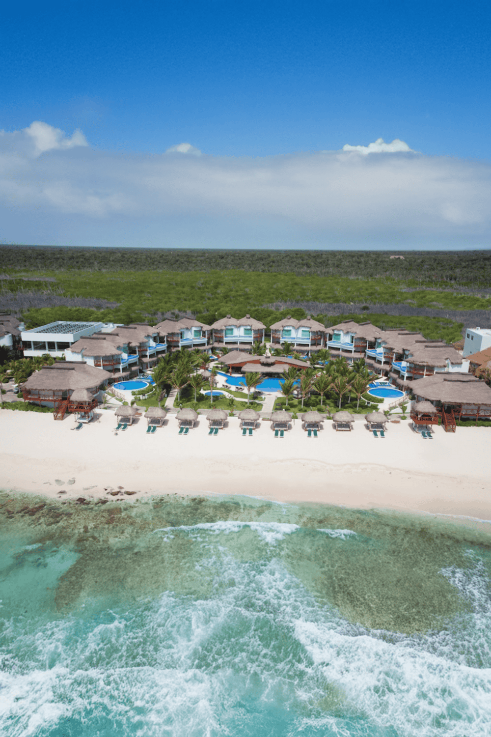 Luxurious beachfront resort with pools, palm trees, and ocean views, perfect for vacation and relaxation.