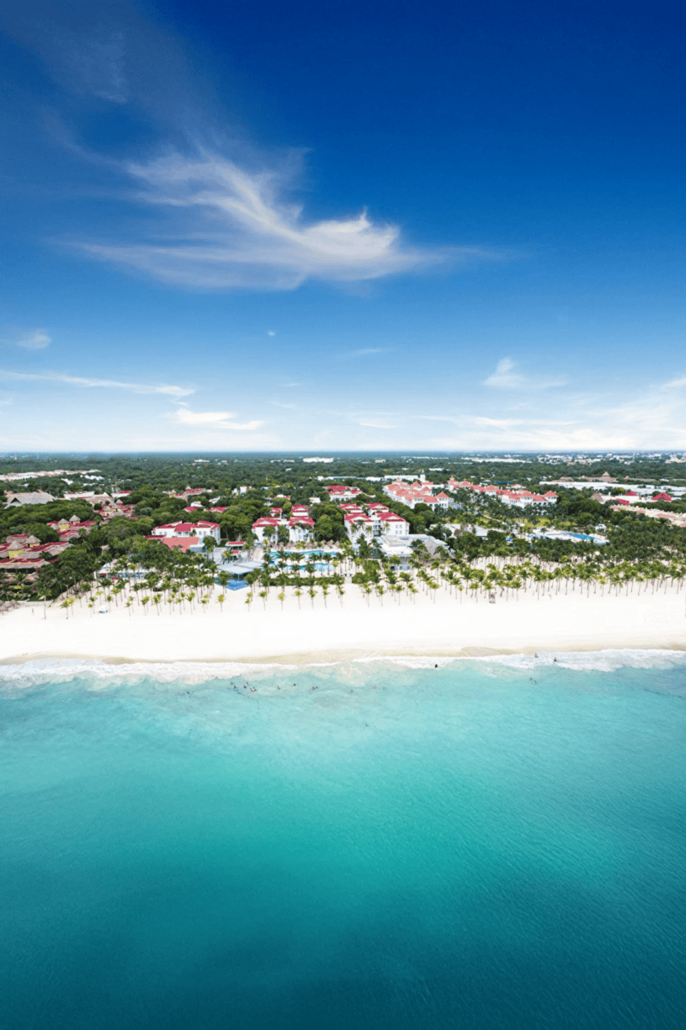 Aerial view of a beachside resort with crystal clear water and lush greenery, perfect for vacation planning.