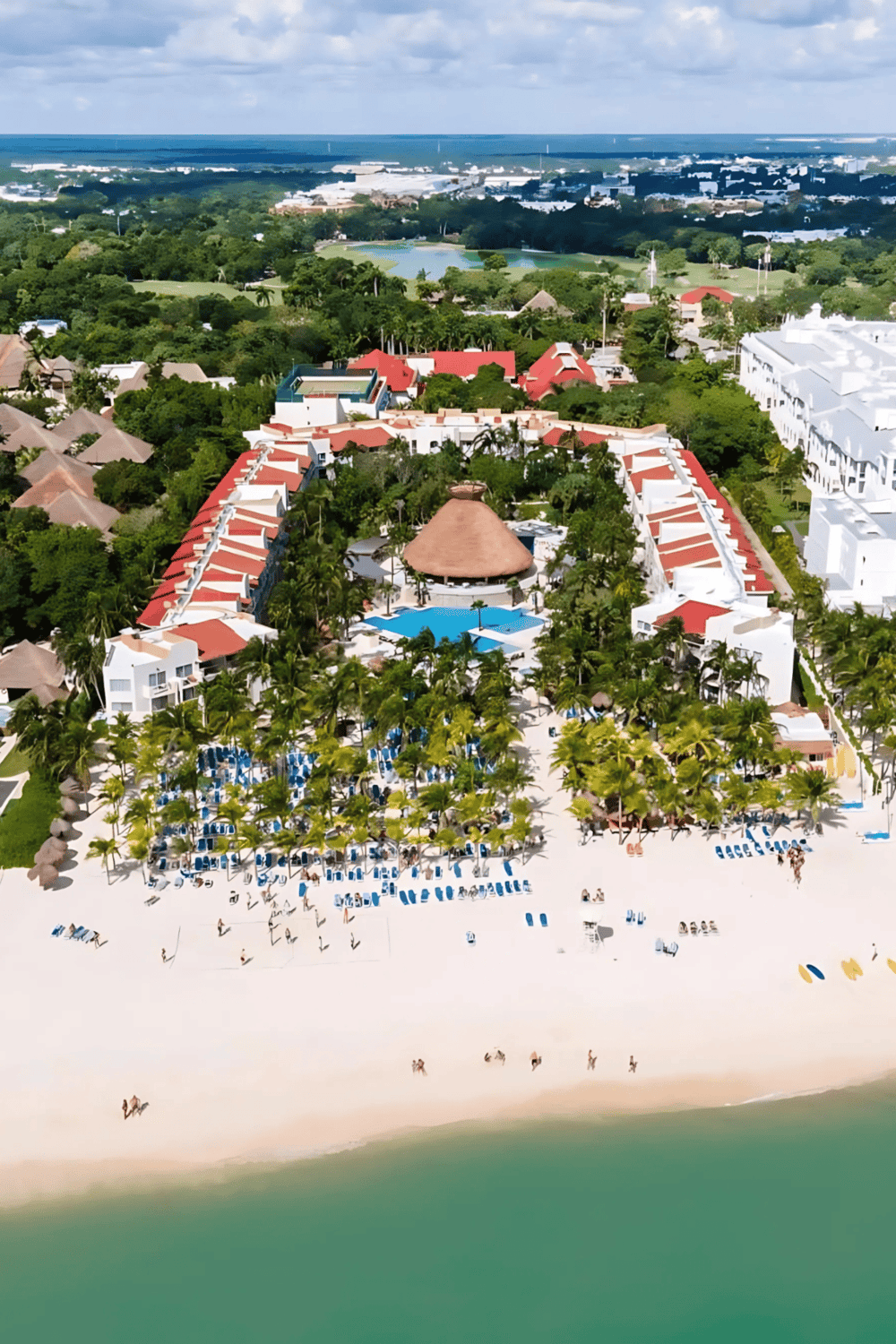 Luxury beach resort with pool, tropical trees, and ocean view in Cancun, Mexico.