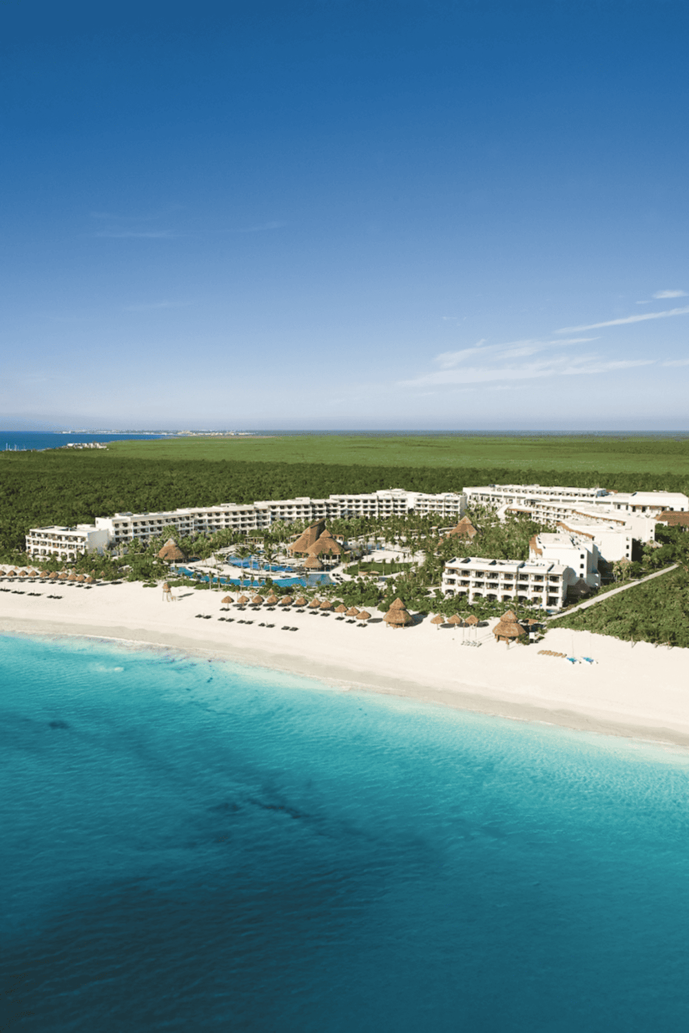 Luxurious beachfront resort with infinity pools and palm trees on white sandy beach in Cancun.