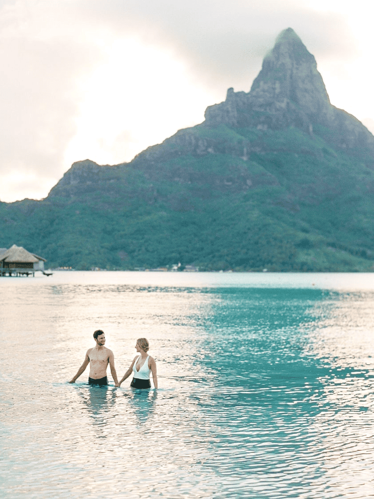 Sunset couples swimming at tropical beach Paradise Island Fiji scenic destination for romance and travel.