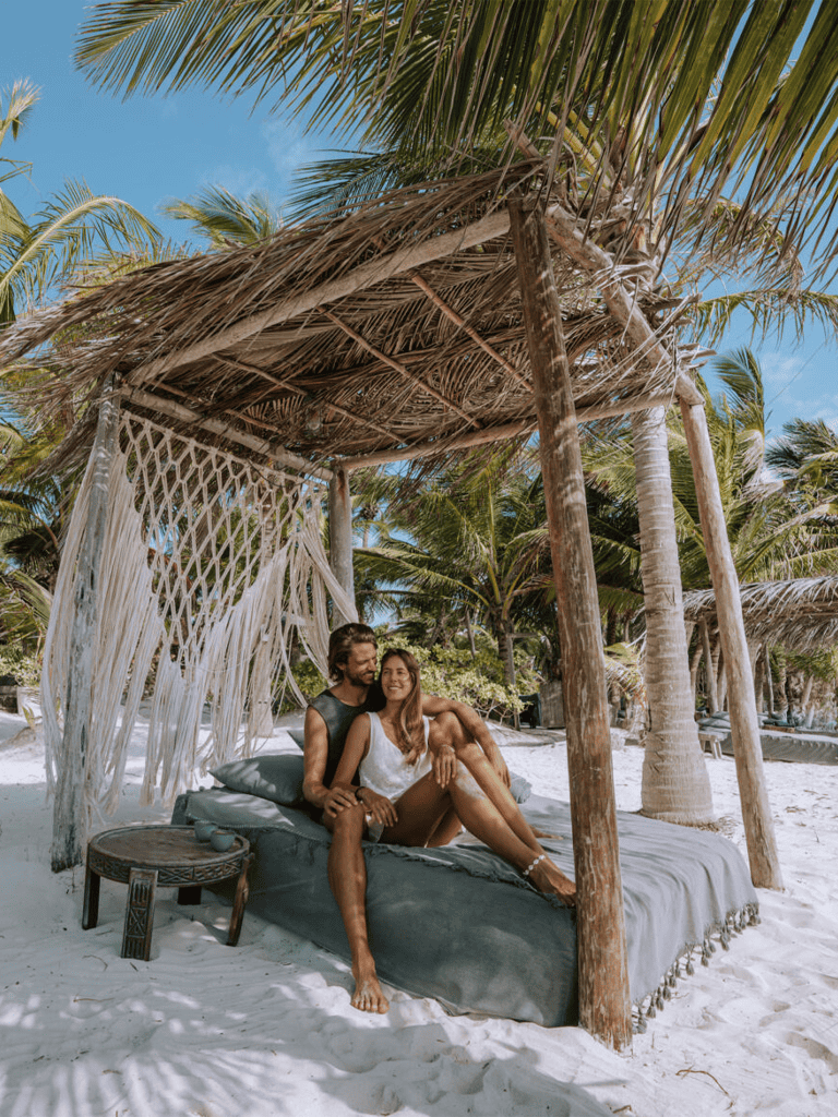 Relaxing beach canopy with palm trees and a couple enjoying a tropical getaway for travel and vacation relaxation.