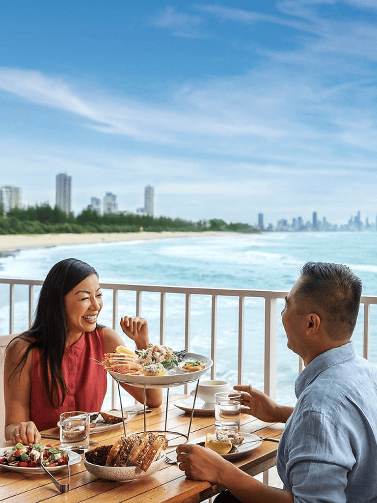 Beachside dining experience with friends, overlooking the ocean and city skyline, perfect for vacations and special occasions.