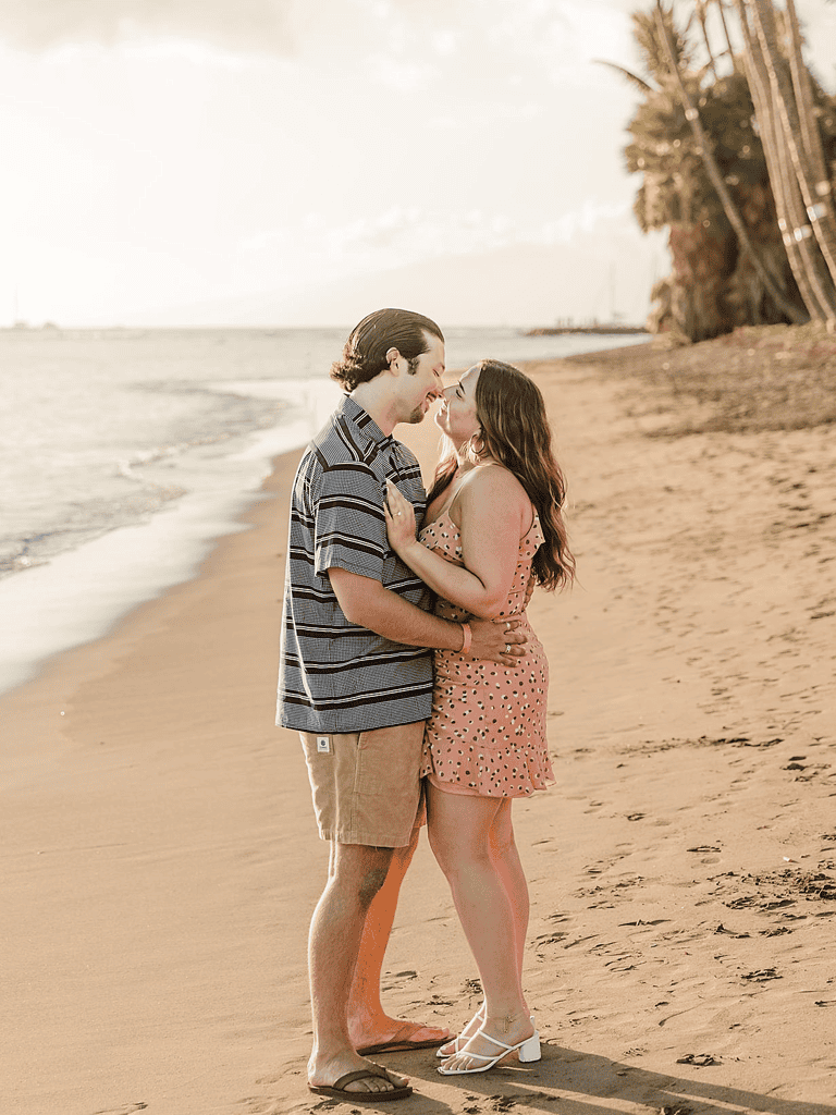 Romantic couple on beach during sunset, embracing and sharing a tender moment.