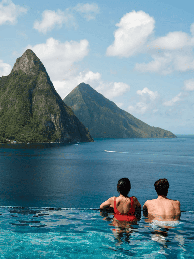 Breathtaking mountain views overlooking a serene infinity pool with two relaxing guests.