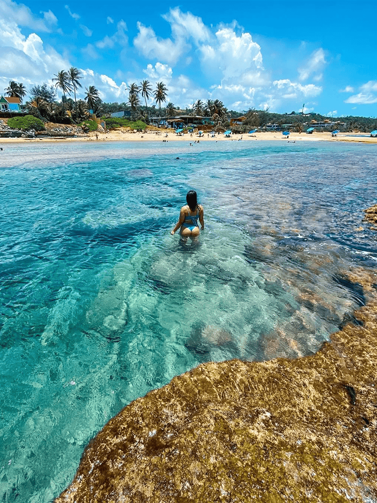 Woman swimming in crystal clear ocean water at tropical beach destination.