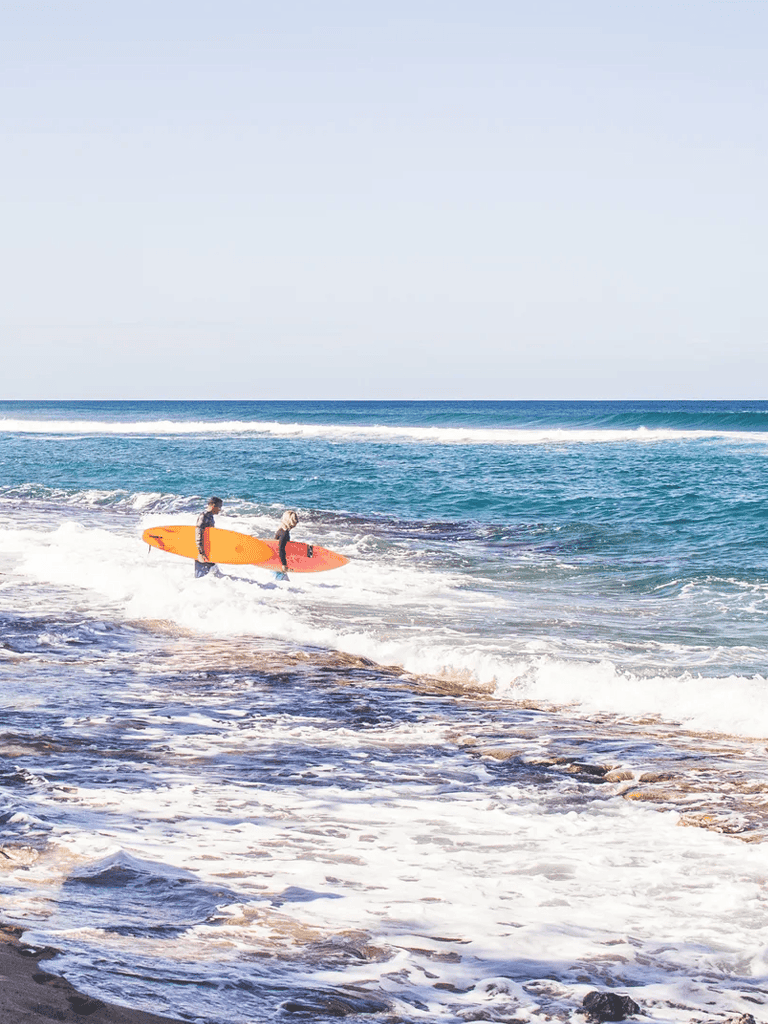 Kids surfing on the beach with a bright sunny sky, perfect summer family vacation destination.