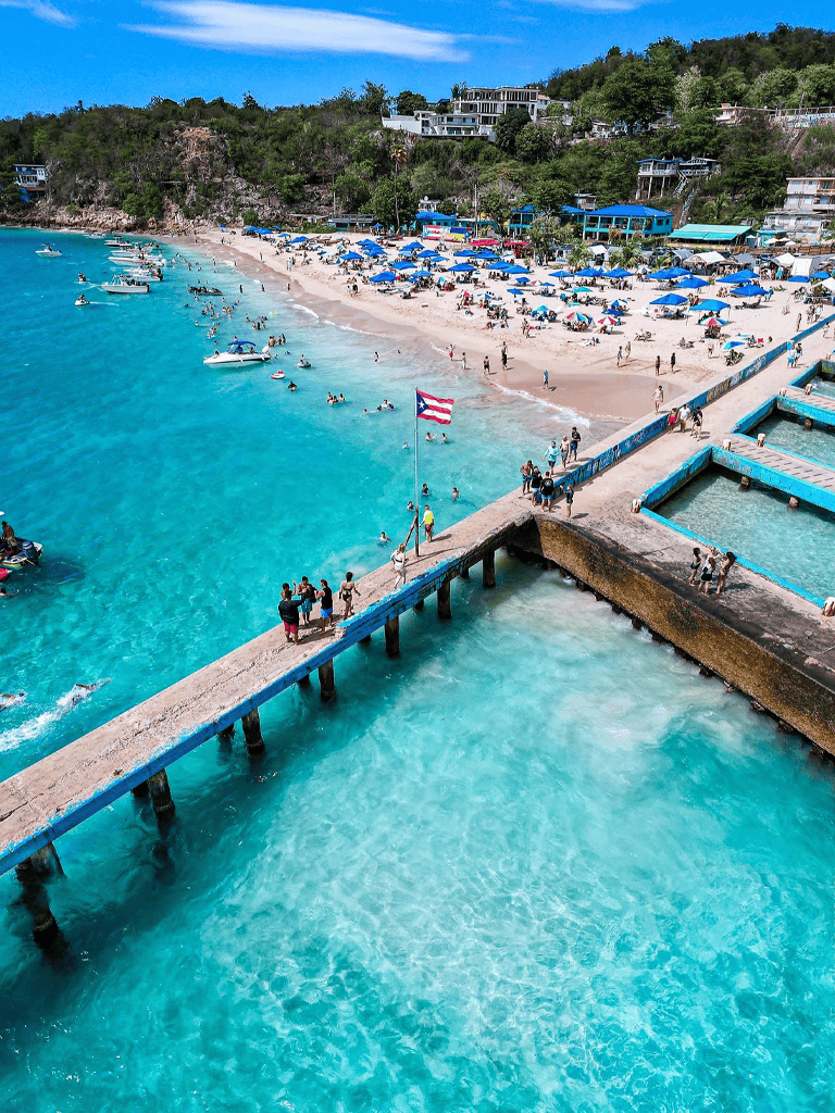Vibrant Puerto Rican beach with clear turquoise waters and sunny parasol-lined shore.