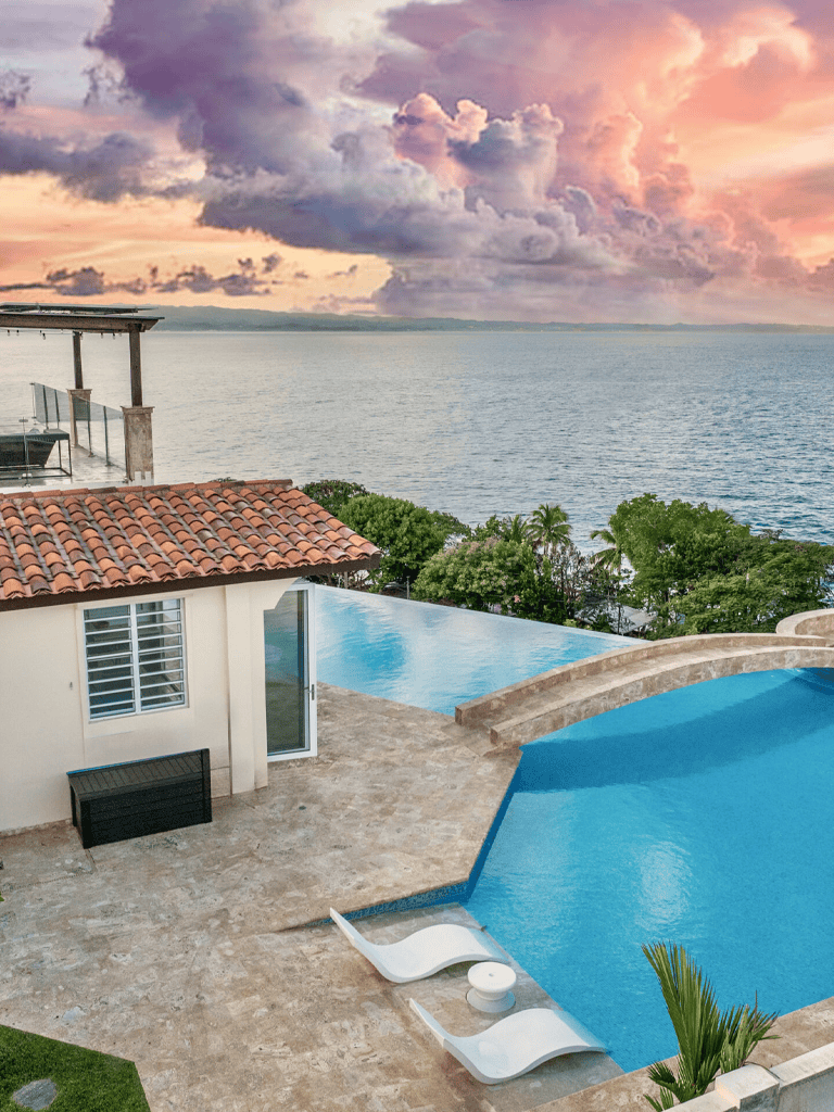Stunning ocean view infinity pool at sunset with tropical surroundings and luxurious amenities.