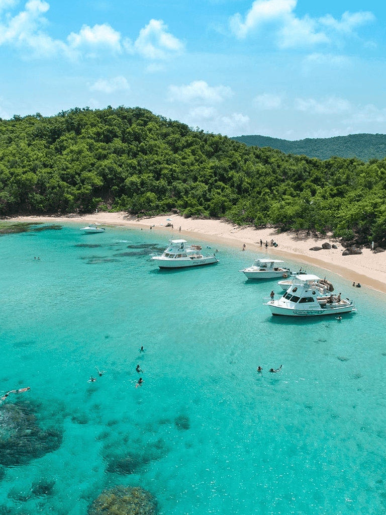 Pristine tropical beach with turquoise waters and boats, perfect for relaxation and water activities.