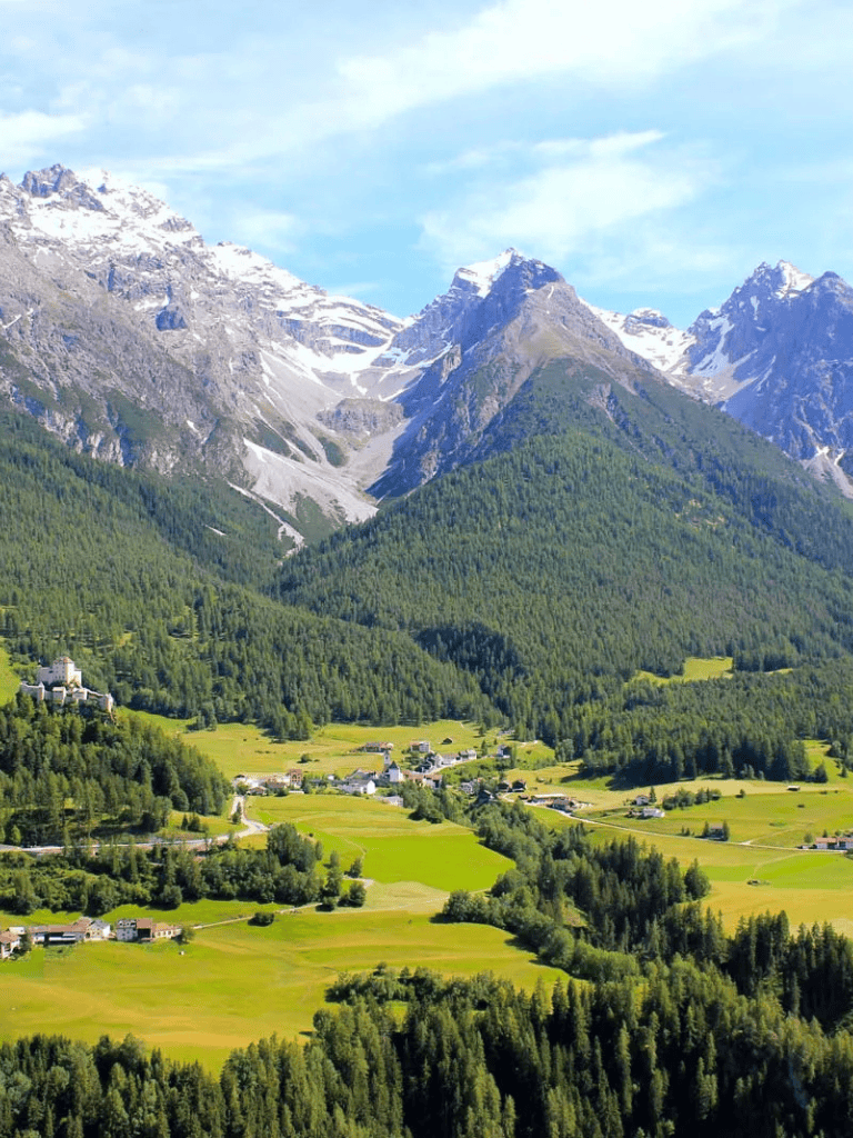 Stunning mountain landscape with lush green valleys and snow-capped peaks in the background.